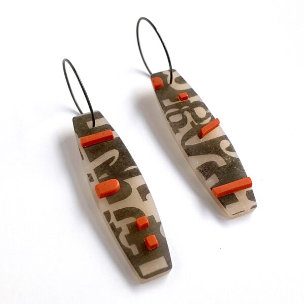 Type collage earrings with orange accents. Polymer clay and sterling silver. Jane Pellicciotto