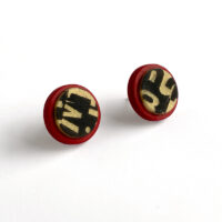Polymer clay circle stud earrings. Red and gold with black letterforms. Jane Pellicciotto