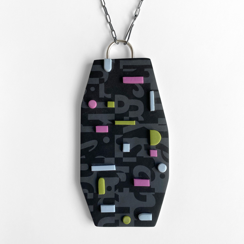 Typographic collage pendant with pastel accents. Polymer clay, sterling silver. Jane Pellicciotto