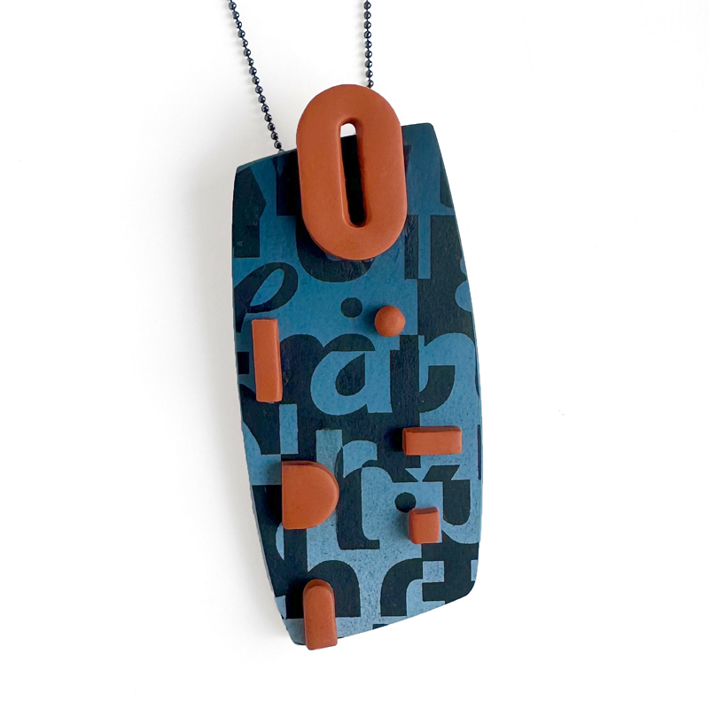 Typographic pendant in blue ombre with raised orange accents. Polymer clay. Jane Pellicciotto